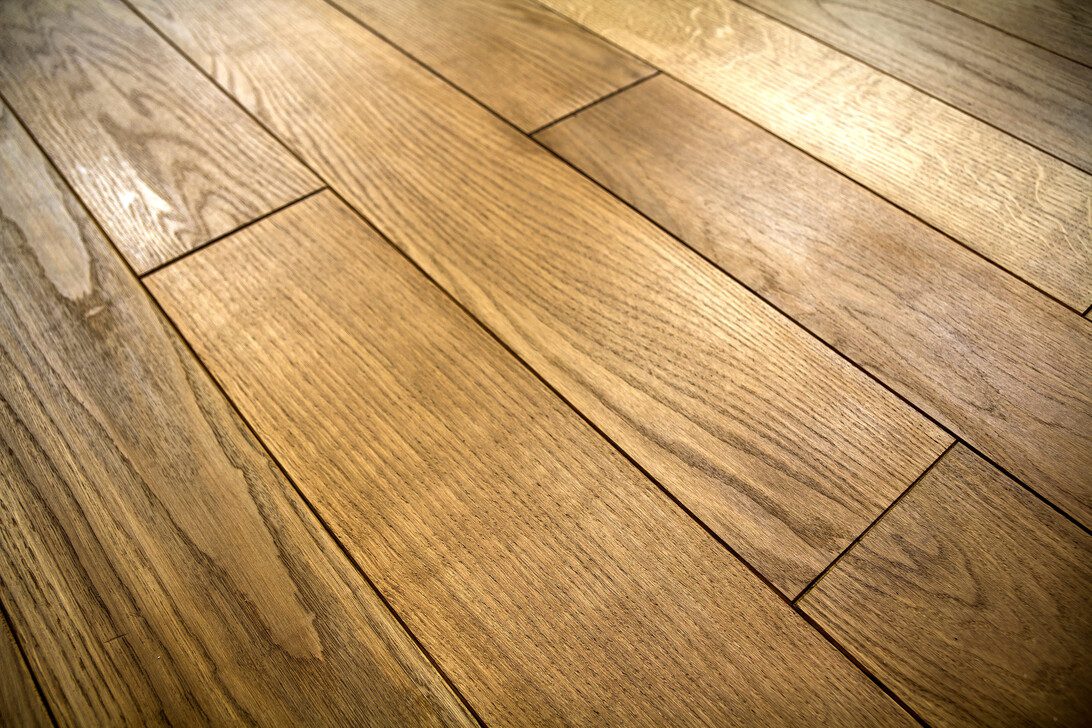 Natural brown texture wooden parquet floor boards - Europa Love 24h Wooden floor with wide brown planks and visible grain running diagonally.